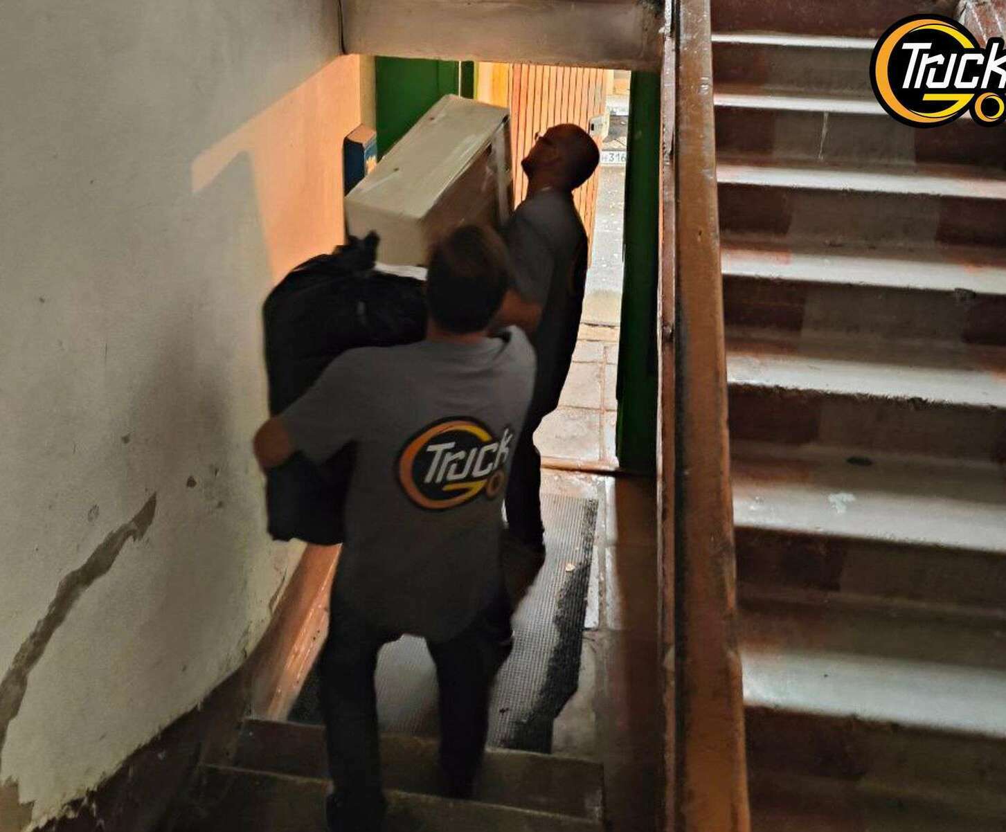 Грузчики выносят мебель из подъезда — Газель у дома в Томске